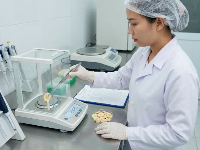 documentary photograph of laboratory technician conducting contaminant testing on freeze dried banana sample
