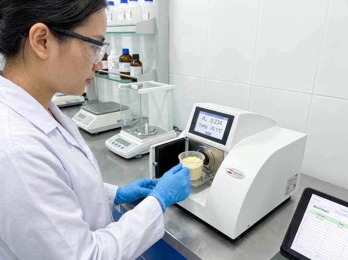 food technologist measuring water activity on a freeze dried banana sample in a quality lab