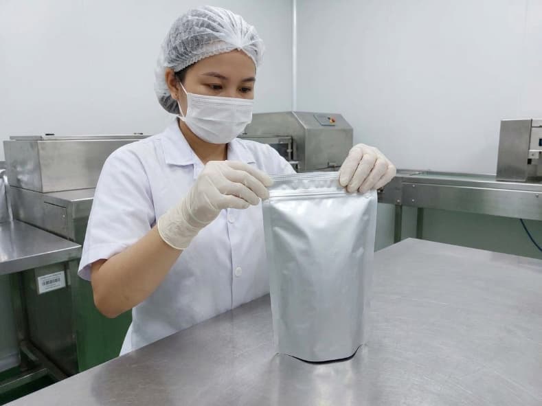 qa inspector checking heat seal integrity on silver foil pouch for freeze dried fruit in vietnam