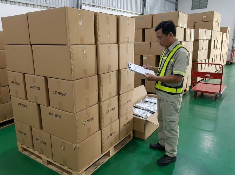 qa officer verifying master carton lot stencils against shipping documents in warehouse.
